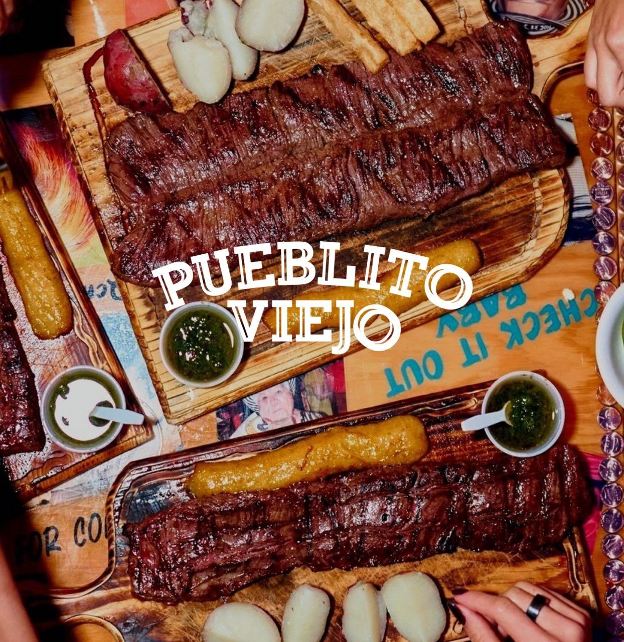 Grilled meat with sauces and sides on wooden boards at Pueblito Viejo restaurant.